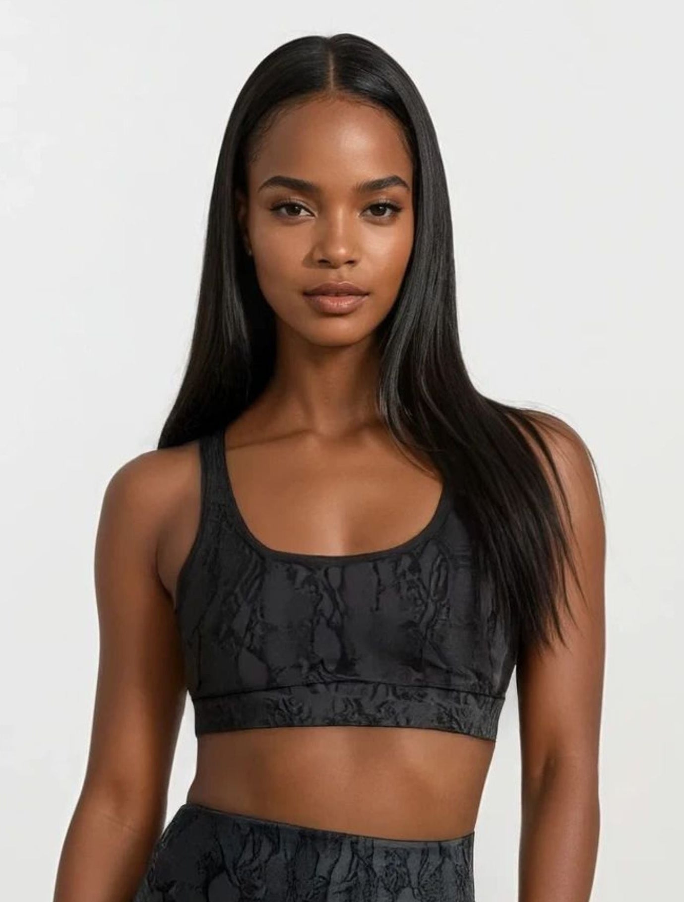 Woman wearing a black patterned sports bra and leggings on a white background