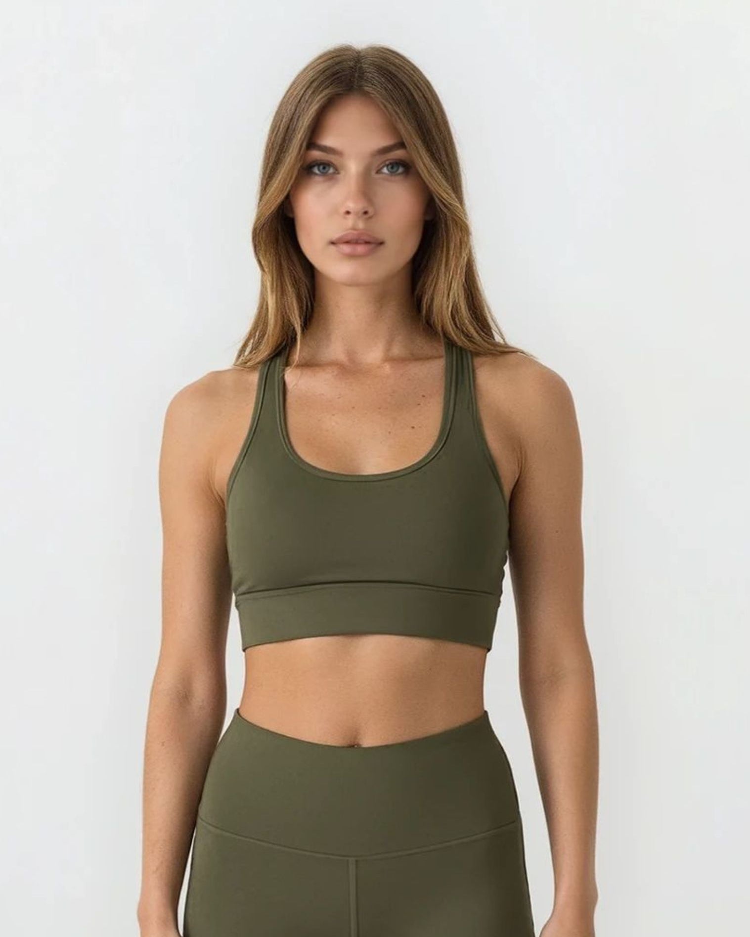 Woman wearing an olive green sports bra and high waist phone pocket leggings