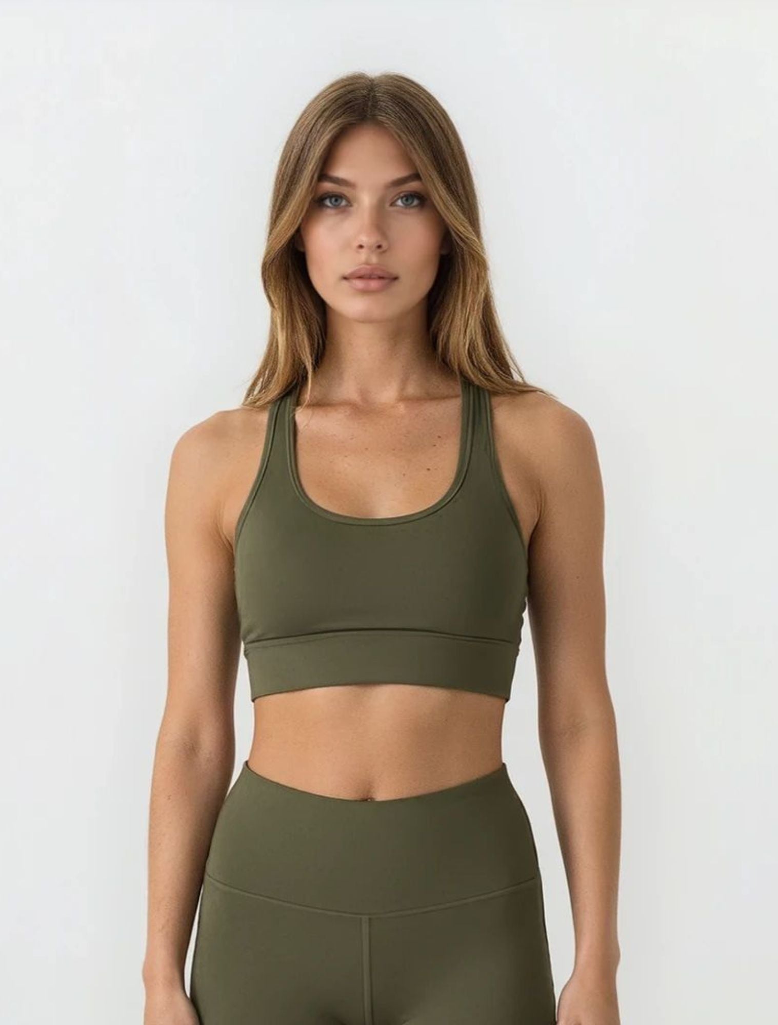 Woman wearing an olive green sports bra and high waist phone pocket leggings