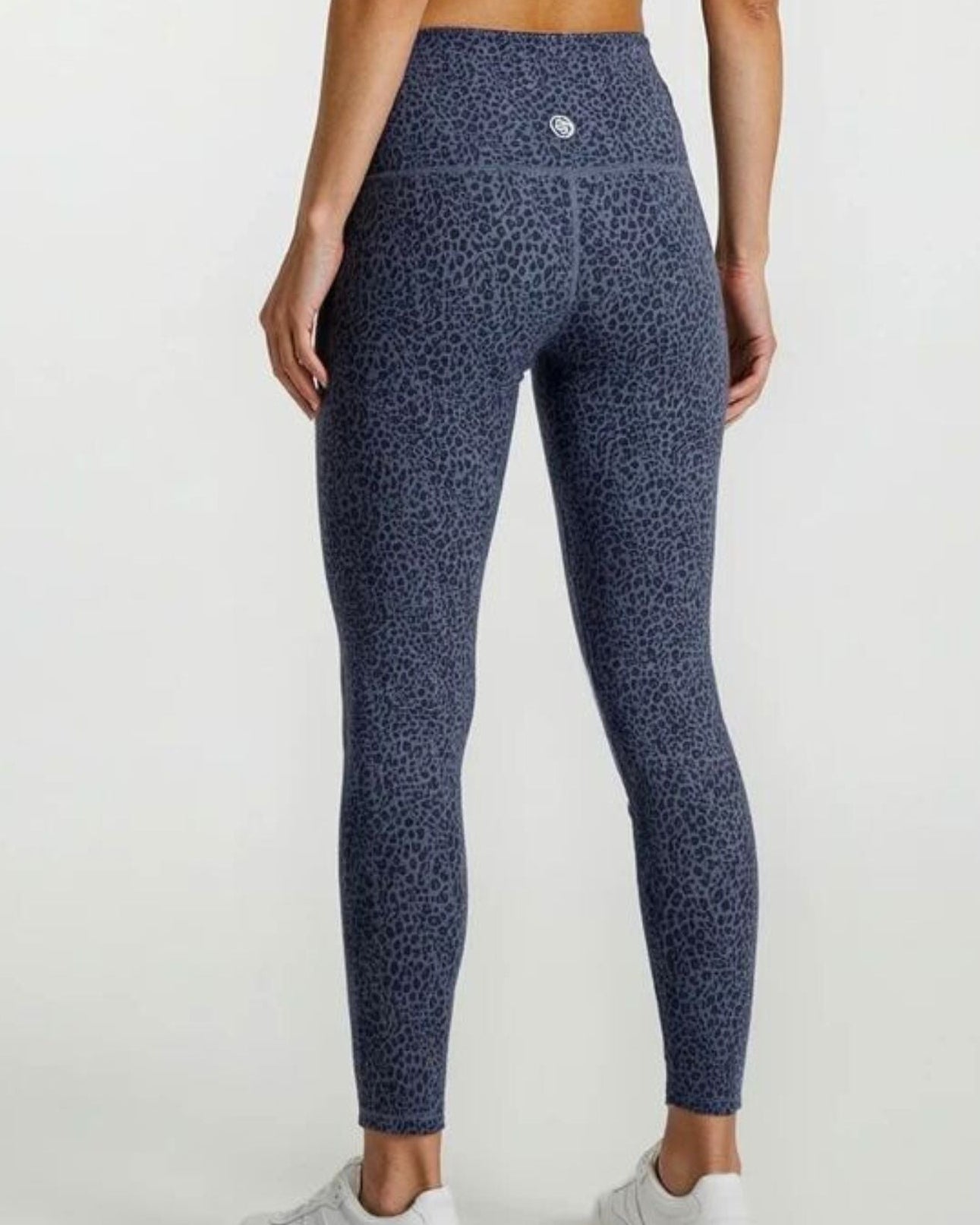 Person wearing blue patterned leggings and a matching top on a white background