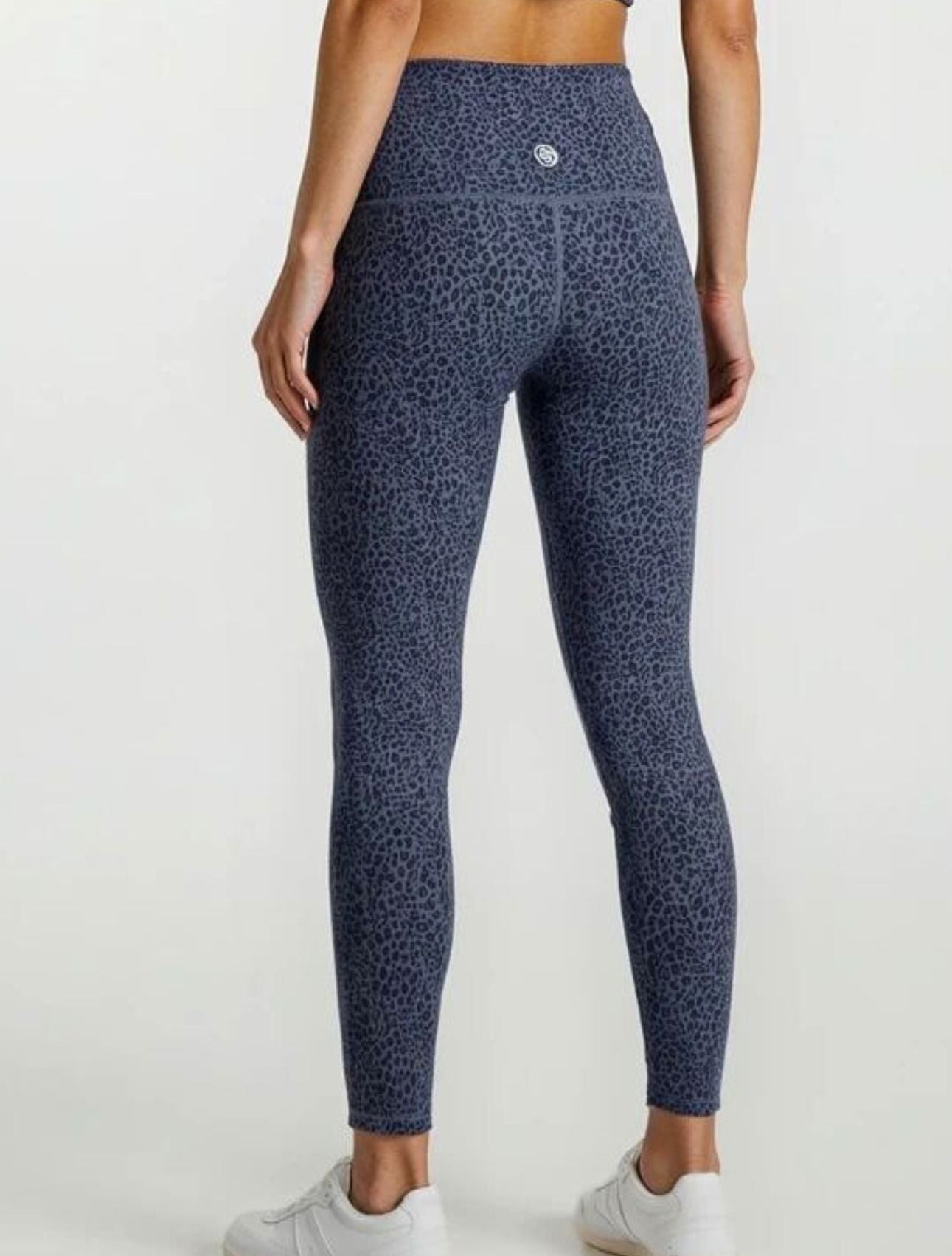 Person wearing blue patterned leggings and a matching top on a white background