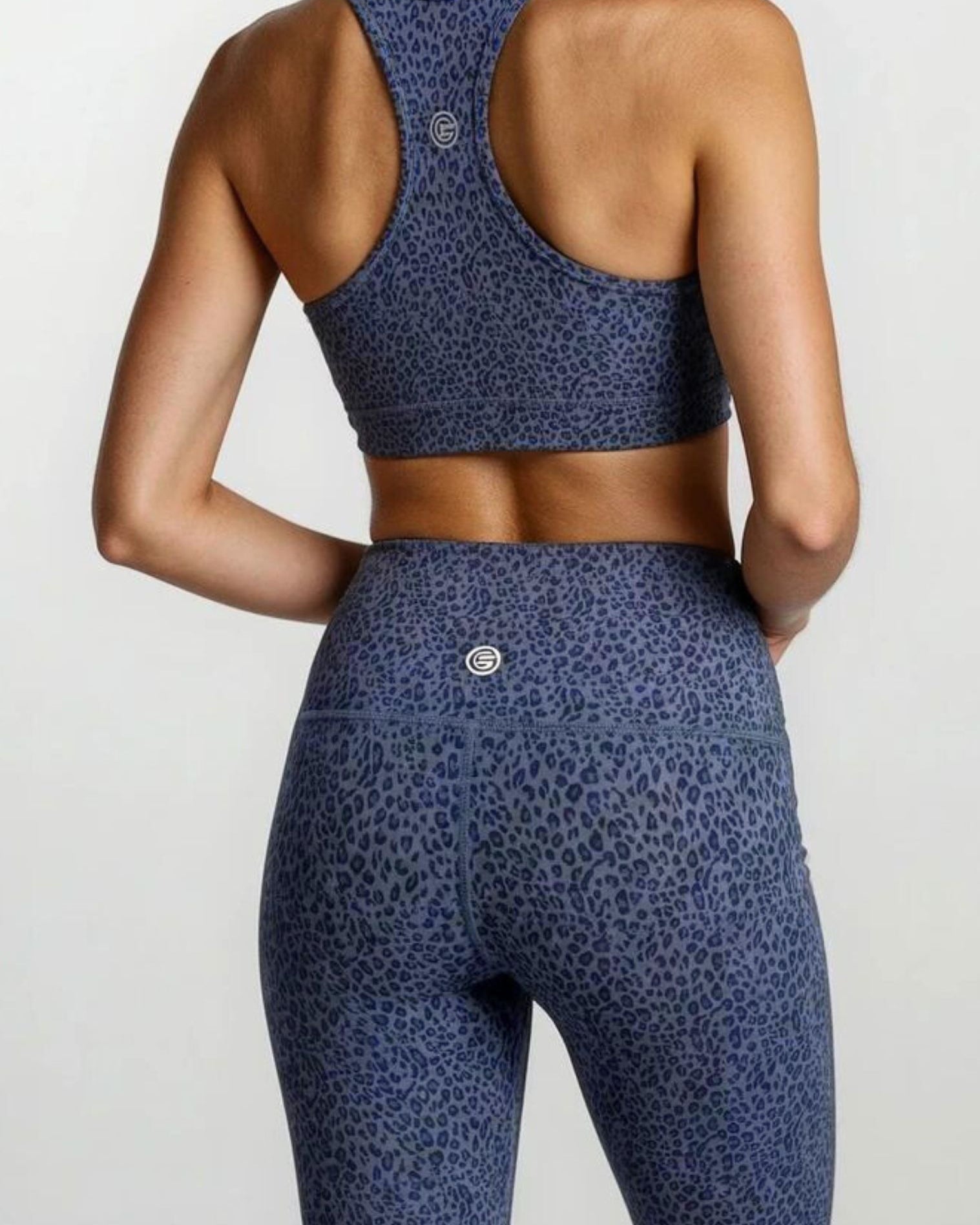 Person wearing a blue leopard print sports bra and leggings in bamboo fabric hypoallergenic active gym and yoga tights on a light gray background