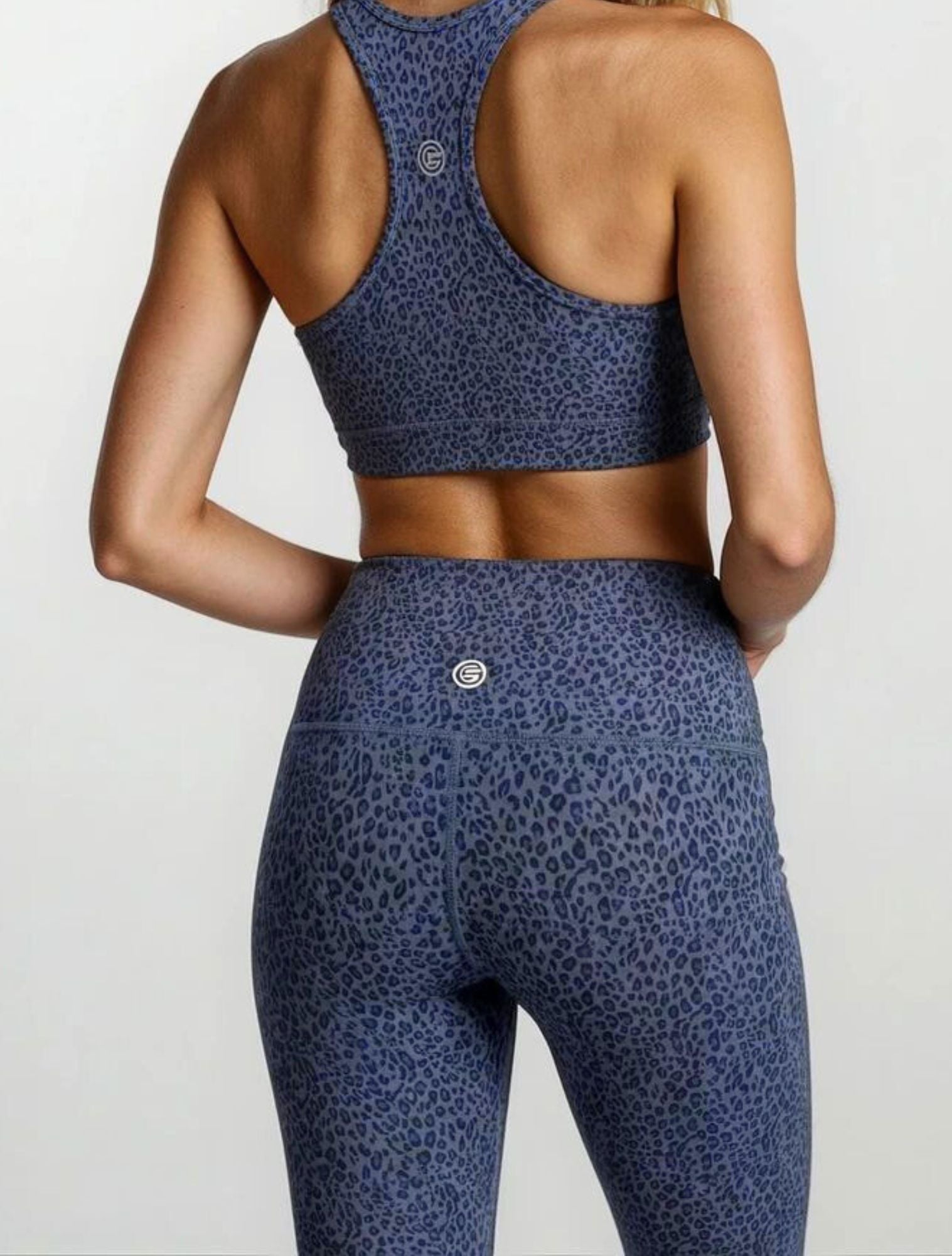 Person wearing a blue leopard print sports bra and leggings in bamboo fabric hypoallergenic active gym and yoga tights on a light gray background