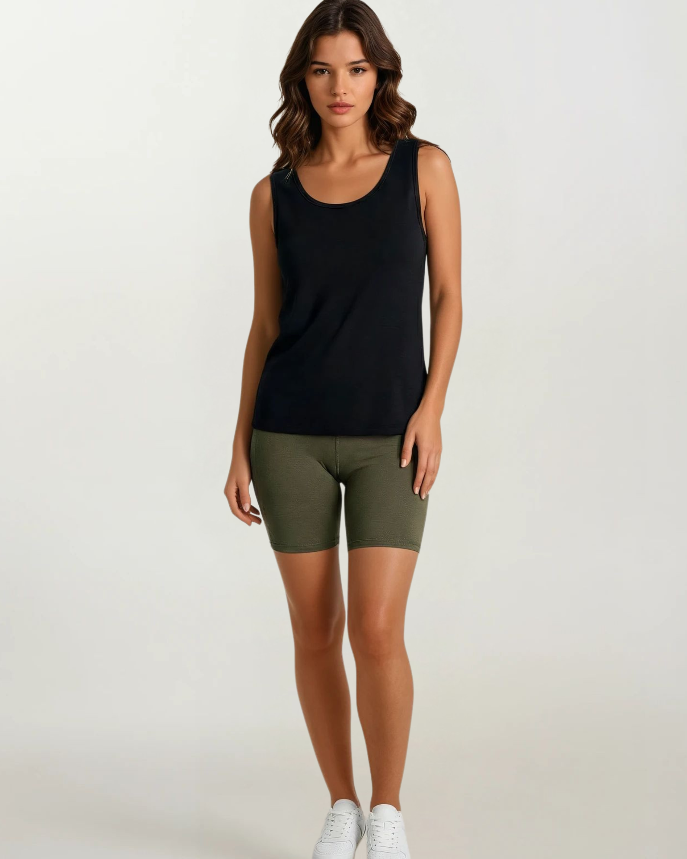 Woman wearing a black tank top and olive green shorts on a white background