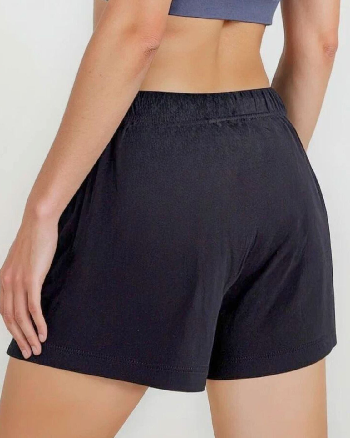 Person wearing a blue sports bra and black shorts on a white background