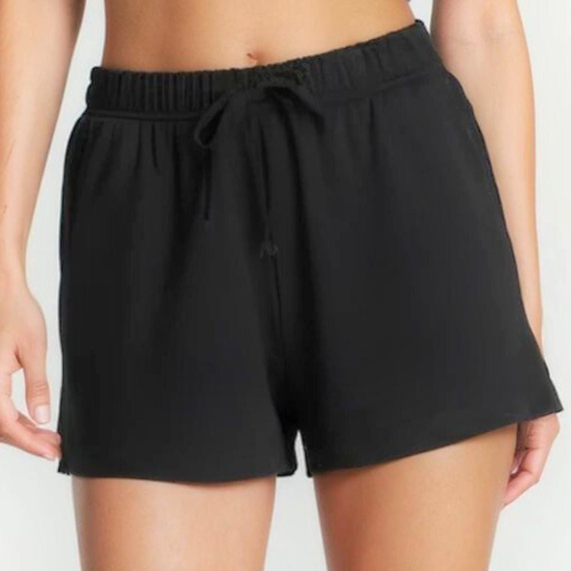Girl wearing black shorts and a gray crop top on a white background
