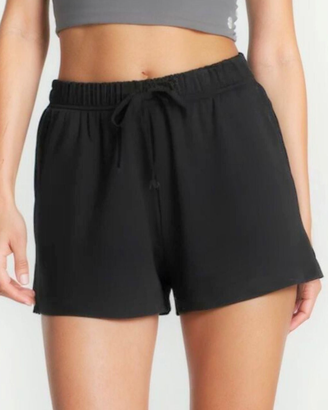 Girl wearing black shorts and a gray crop top on a white background