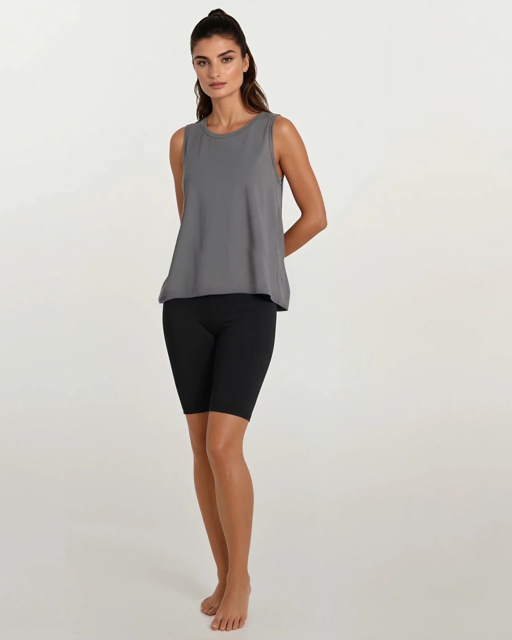 Woman wearing a gray sleeveless tank top and black shorts on a white backgroundbackground