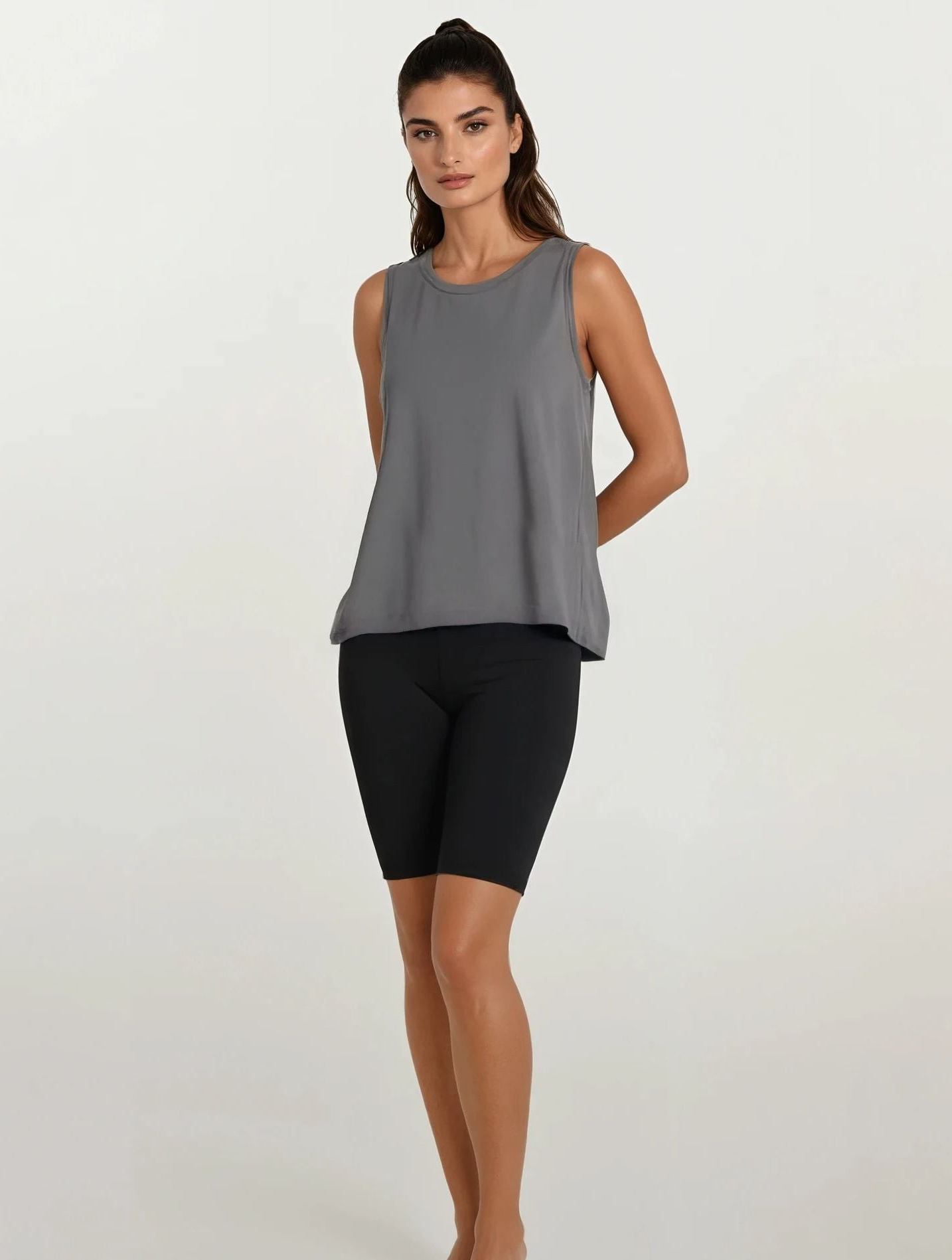 Woman wearing a gray sleeveless top and black shorts on a white background