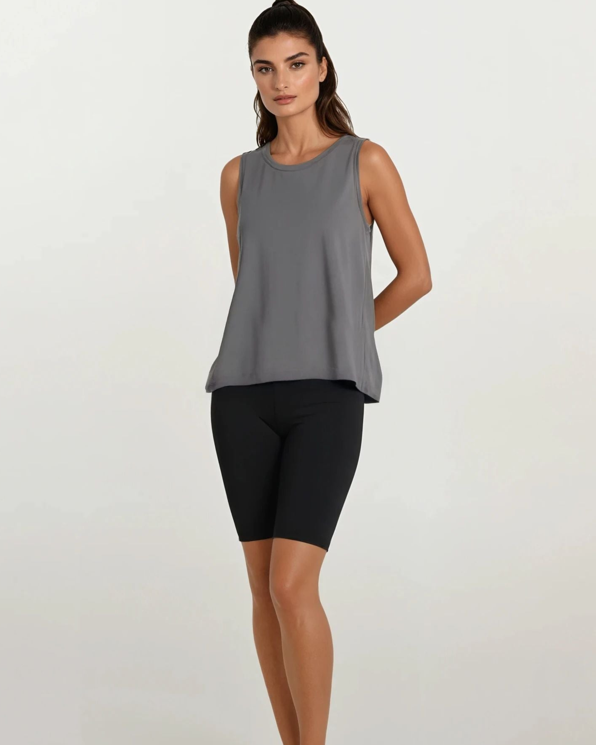 Woman wearing a gray sleeveless top and black shorts on a white background