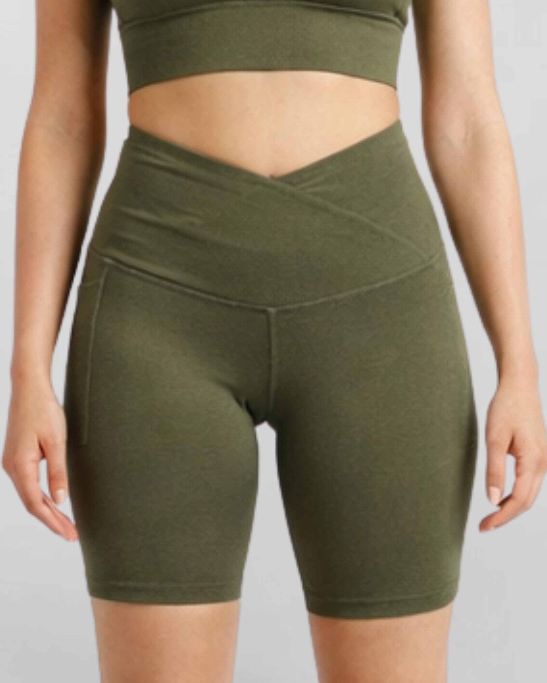 Woman wearing olive green athletic shorts Motion Khaki Bike Shorts Cross V Waist Bamboo soft and moisture wicking gym yoga pilates short sustainable skin friendly on a plain background