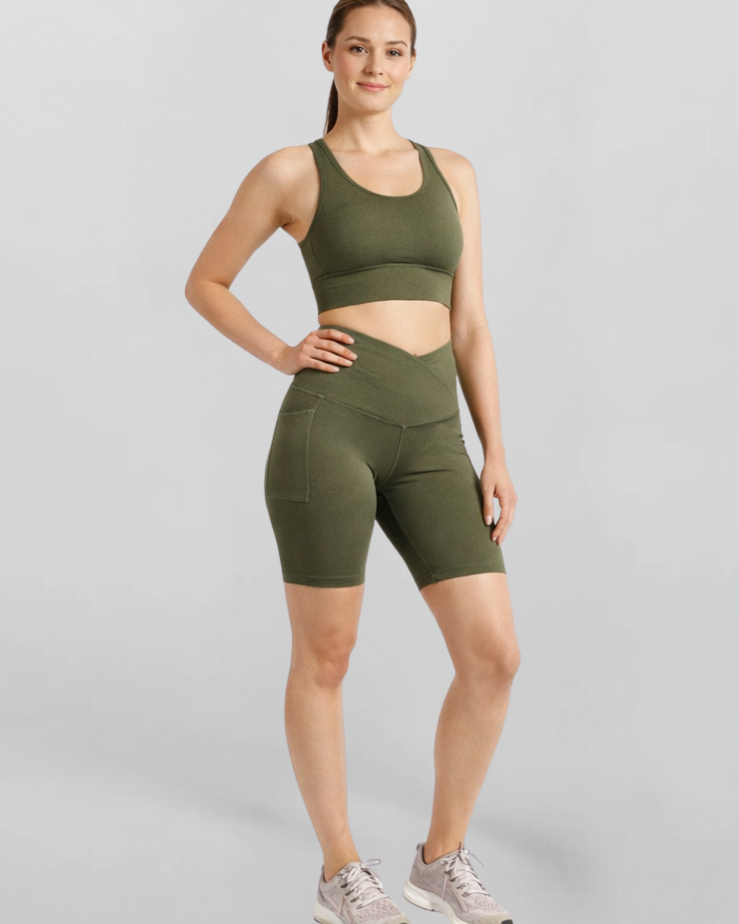 Woman wearing an olive green athletic outfit Motion Khaki Cross V Waist Bike Shorts Bamboo soft and moisture wicking performance gym yoga pilates short on a gray background