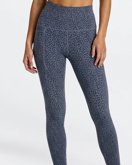 Woman wearing a leopard patterned animal print phone pocket leggings in super soft bamboo on a white background
