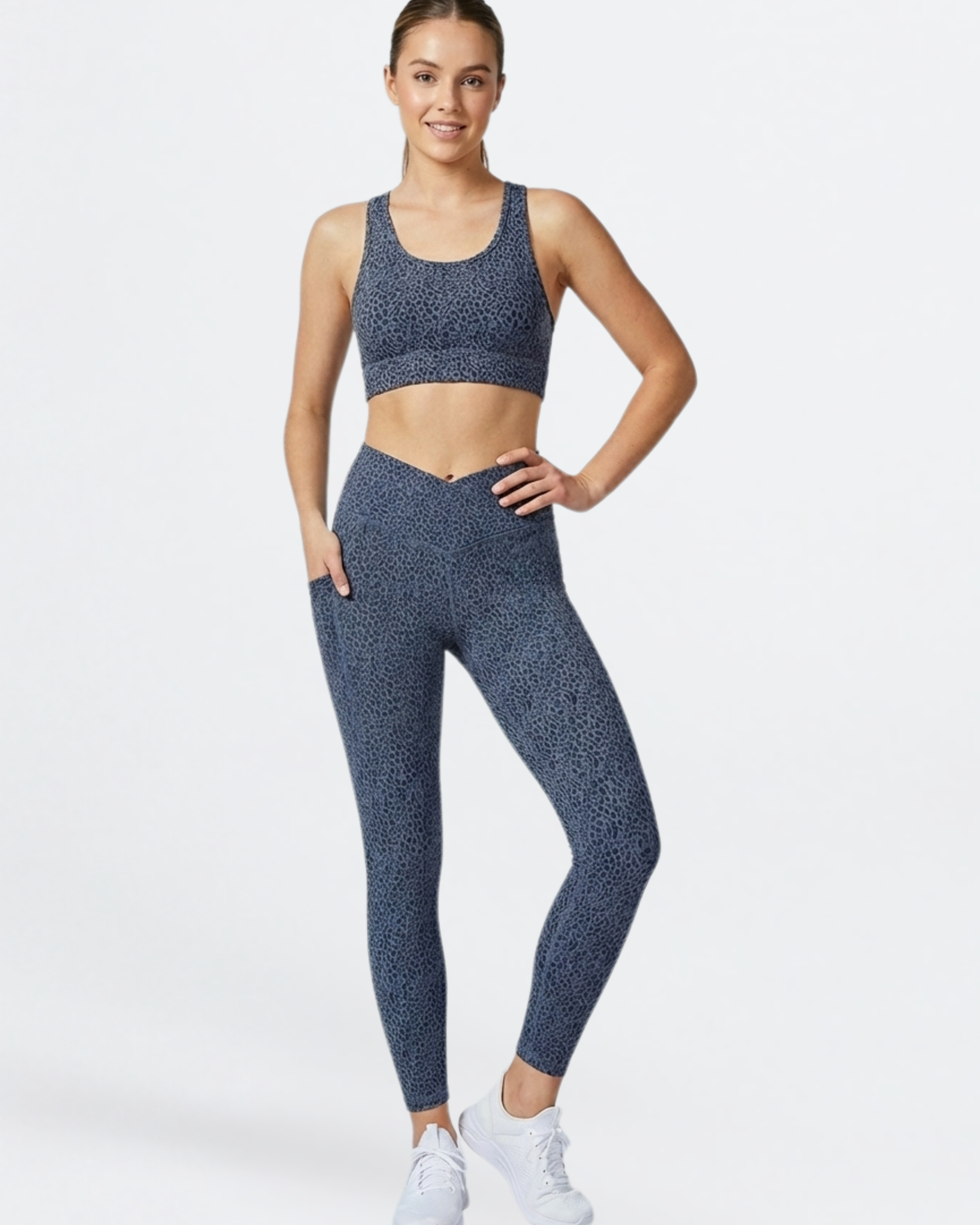 Woman wearing a blue patterned sports bra and phone pocket leggings set of Teal Blue Paw Print Bamboo Swift Cross Leg Legging on a white background