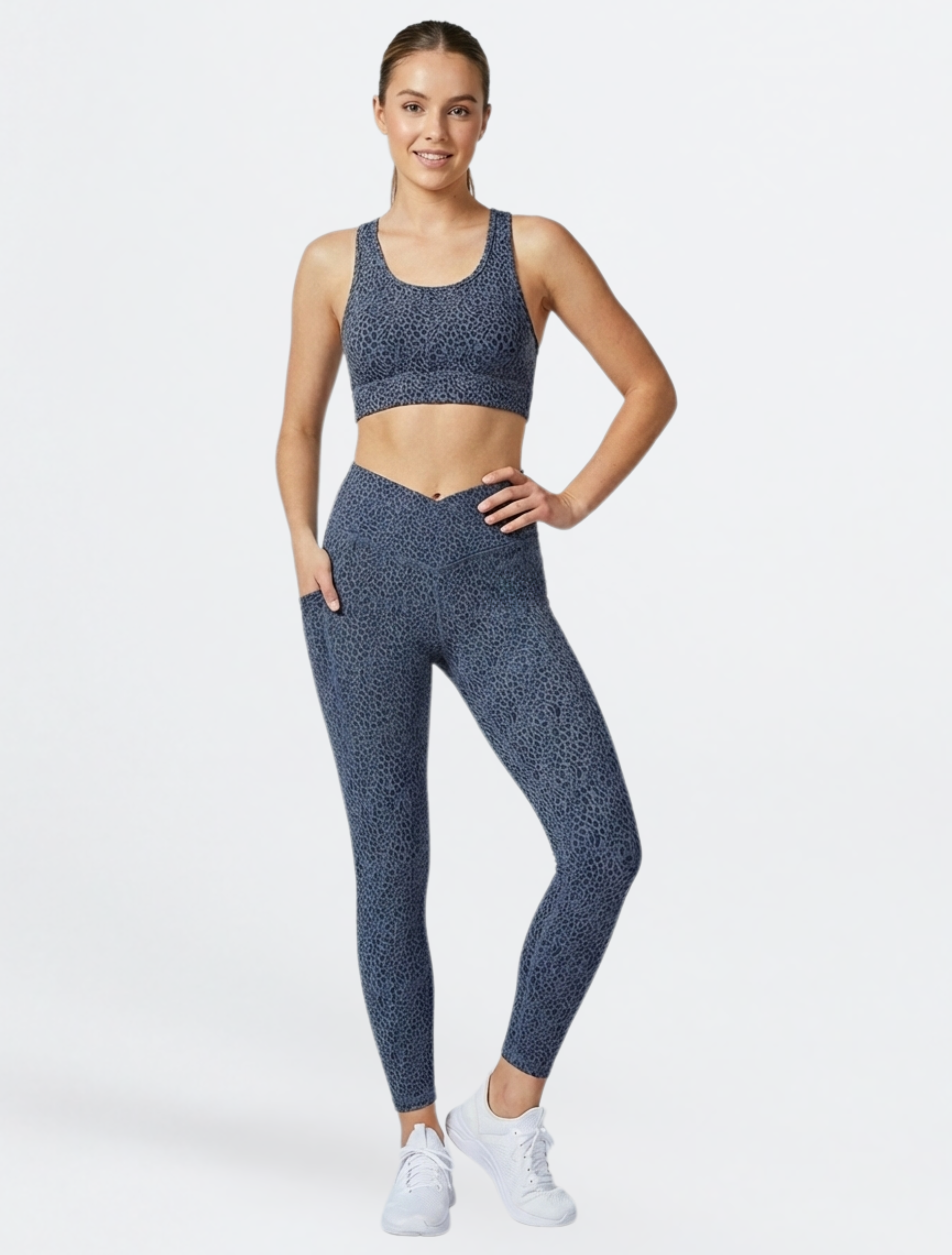 Woman wearing a blue patterned sports bra and phone pocket leggings set of Teal Blue Paw Print Bamboo Swift Cross Leg Legging on a white background
