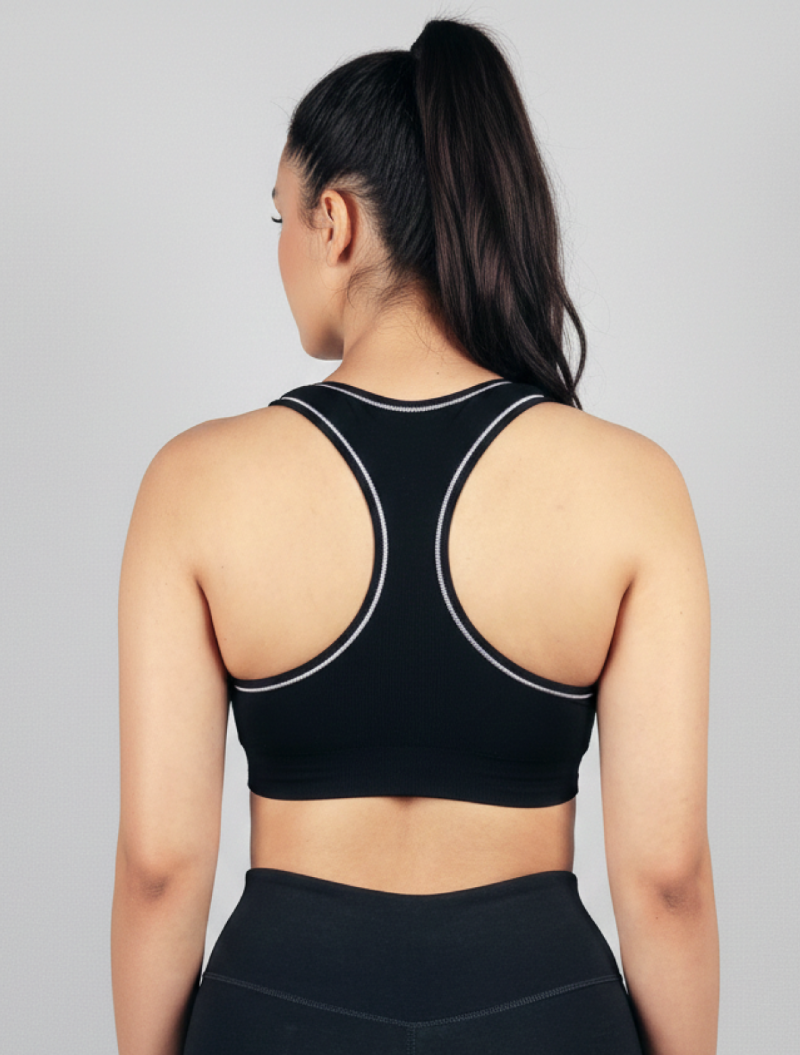 Person wearing a black sports bra with tank top straps Womens Black ribbed-seamless-wirefree-sports bra-Bamboo super soft hypoallergenic breathable Tank Top on a gray background