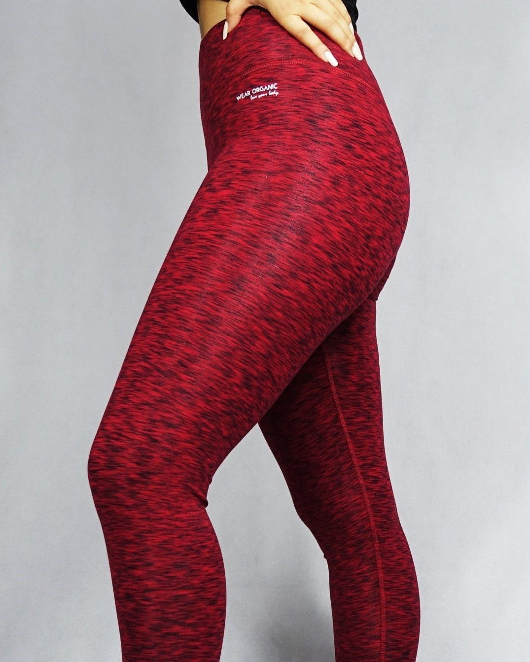 Side view of a model wearing red full length leggings, activewear
