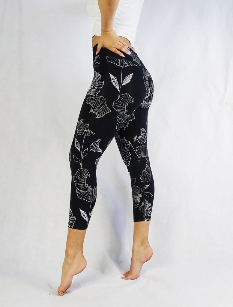 Side view of a women wearing black crop leggings with white flowers