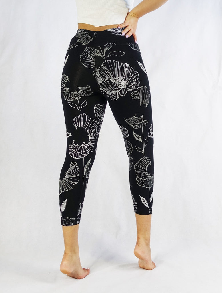 Back view of a model wearing black crop leggings with white floral prints