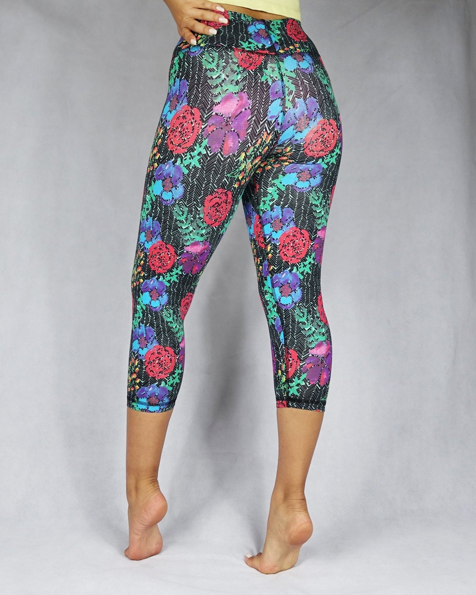 Back view of a model wearing crop legging of red, blue and green flowery prints