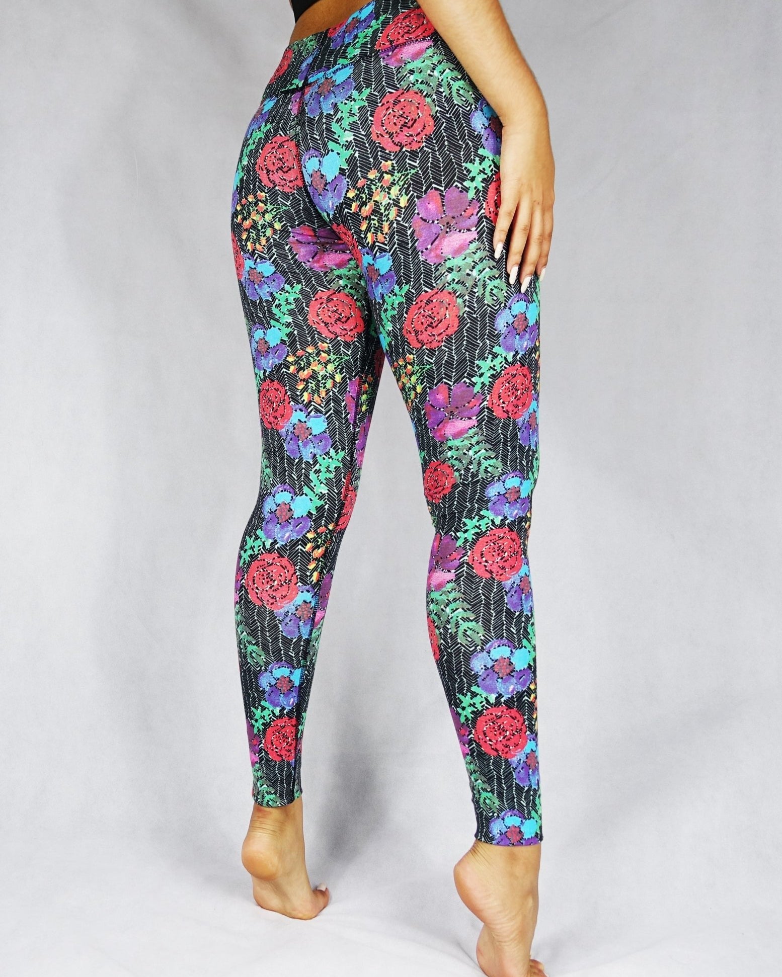 Back view of model wearing full length legging with a red, blue and green flowery prints
