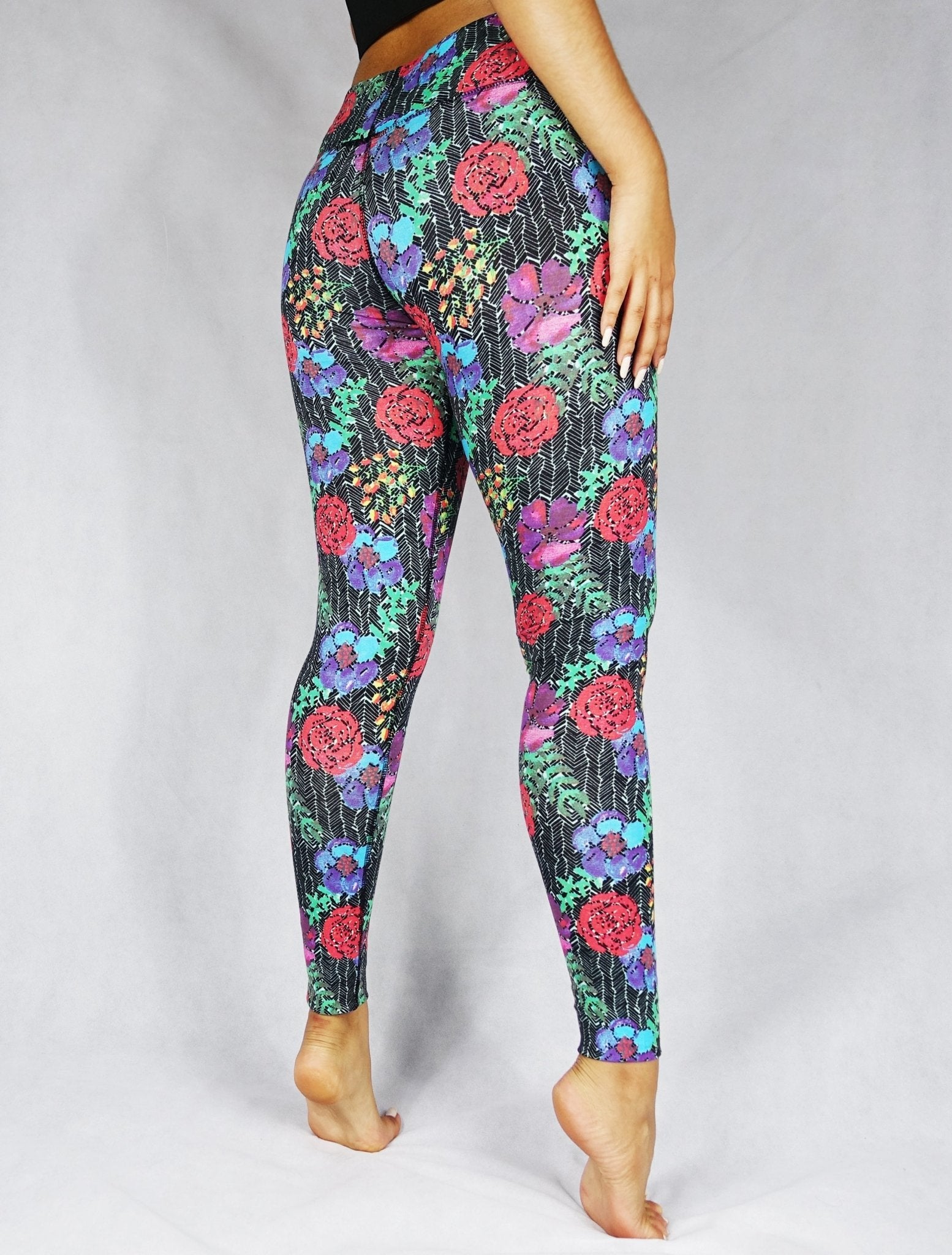 Back view of model wearing full length legging with a red, blue and green flowery prints