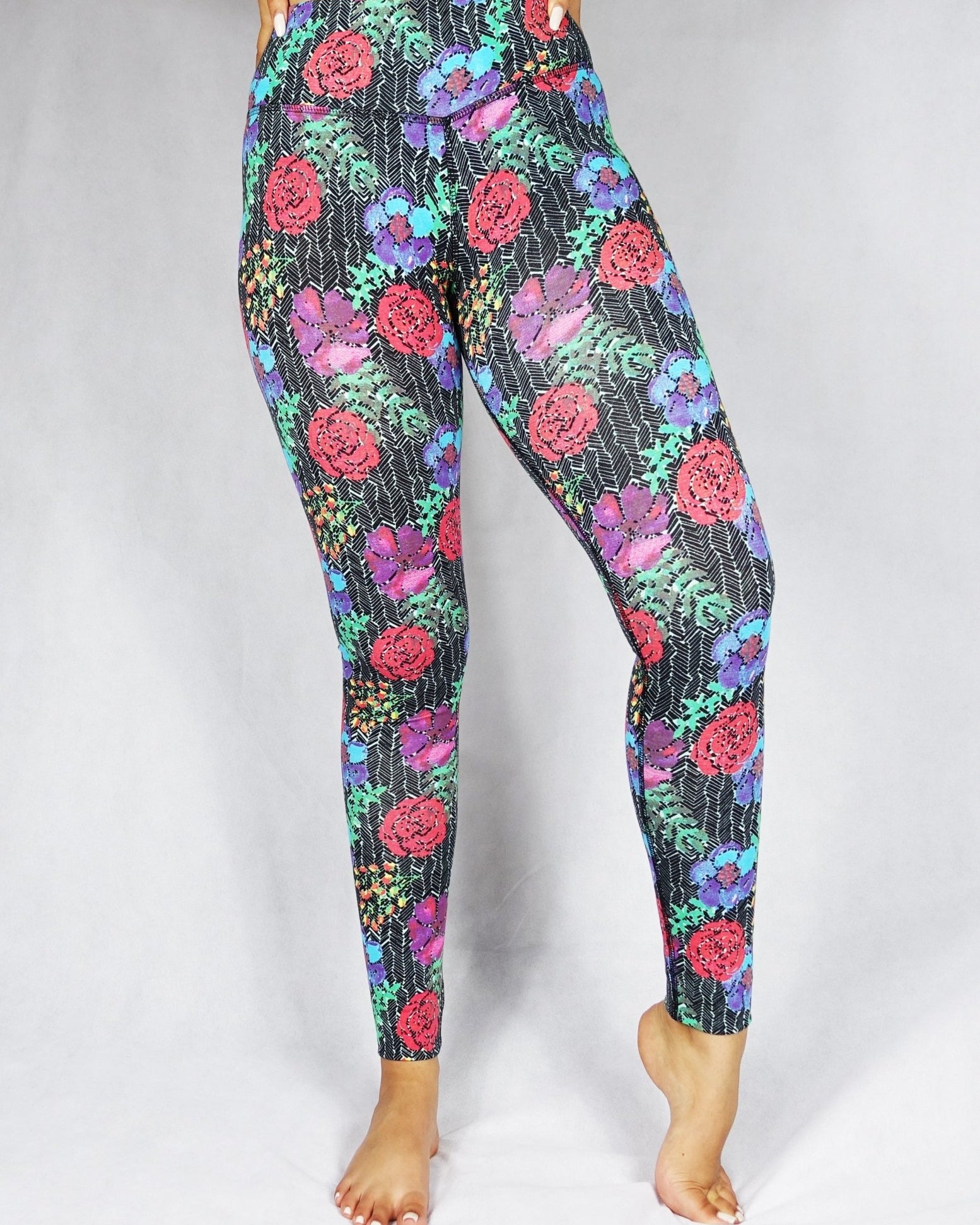 Front view of a model wearing full length legging with a red, blue and green flowery prints