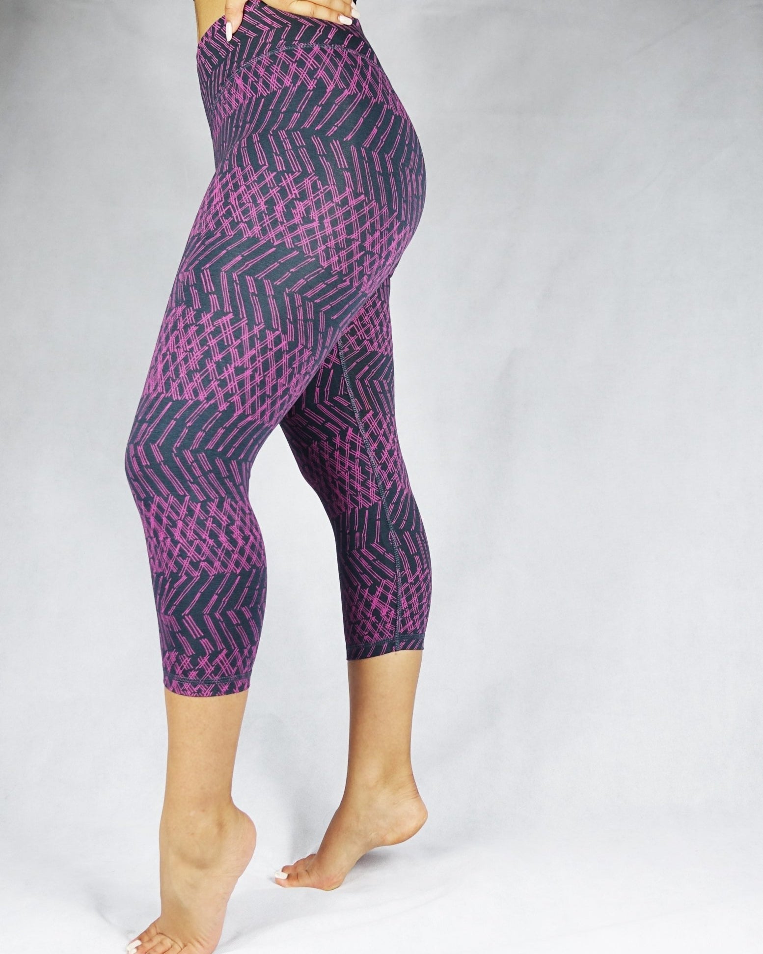 Side view of model wearing plum coloured patterned crop leggings
