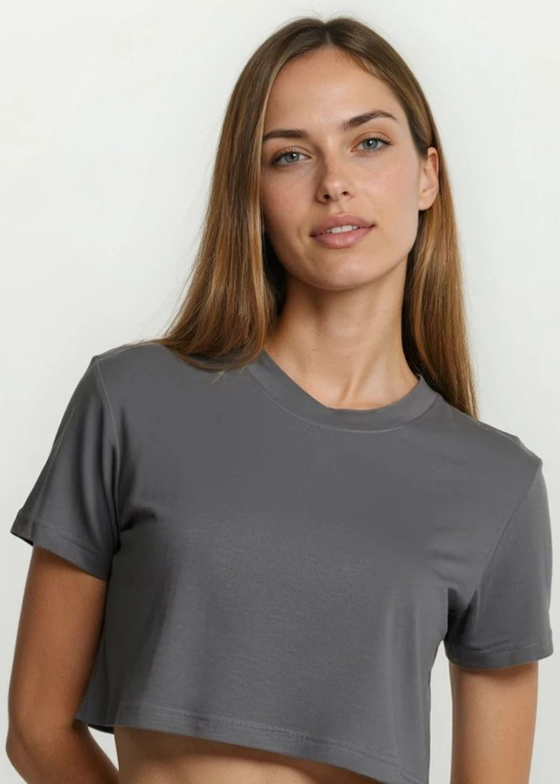 Woman wearing a gray crop top and gray pants against a white background