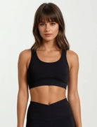 Woman wearing a high impact super soft bamboo black sports bra and leggings on a white background