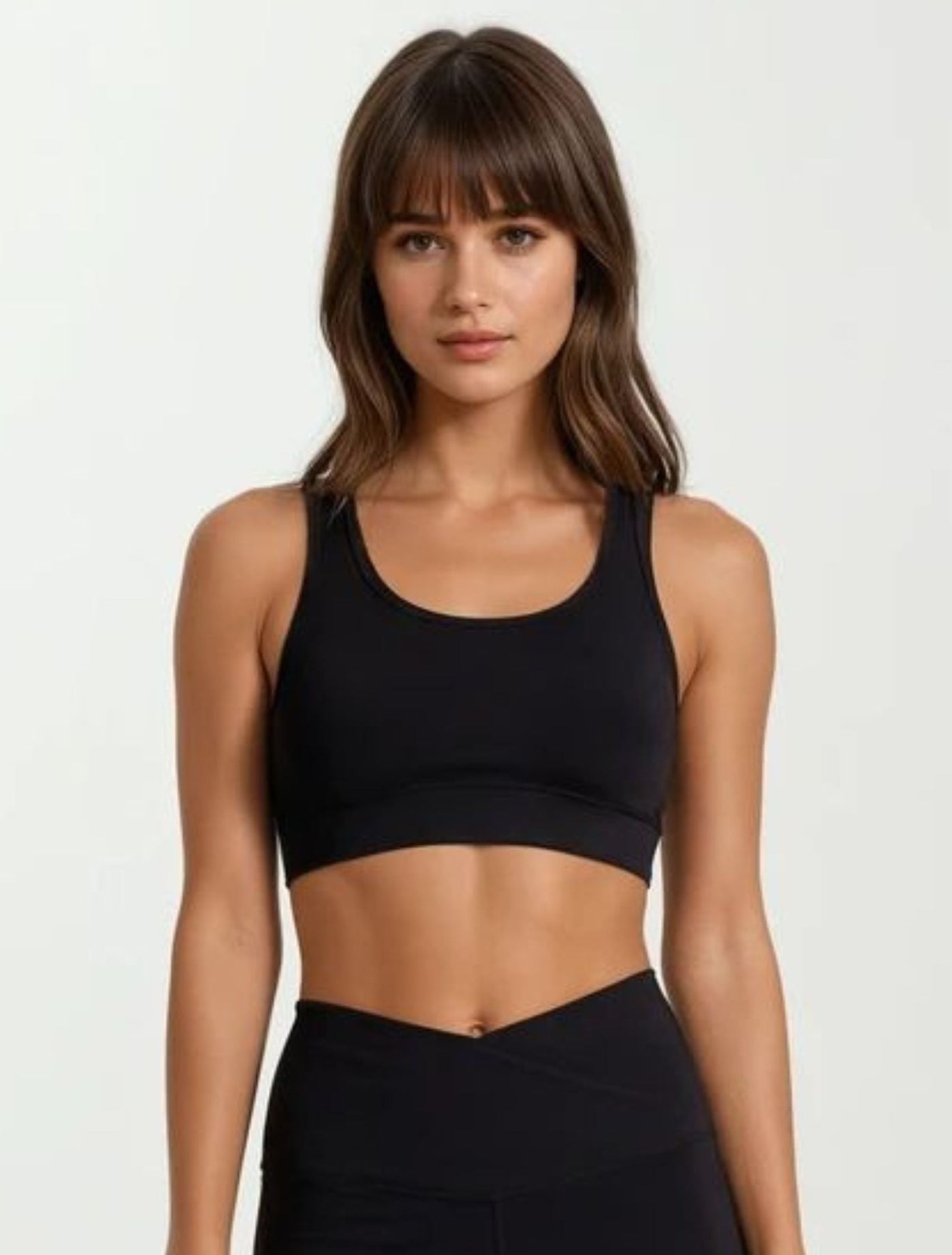 Woman wearing a high impact super soft bamboo black sports bra and leggings on a white background