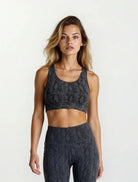 Woman wearing a dark gray snake skin design bamboo high impact sports bra and leggings set on a white background