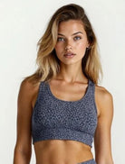 Woman wearing a blue patterned sports bra and leggings Teal Blue Paw Print Bamboo Swift Legging Super Soft Breathable Hypoallergenic_ Active by GS on a white background