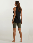 Woman wearing a black sleeveless top and green shorts on a white background