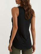 Woman wearing a black sleeveless top and green pants on a white background