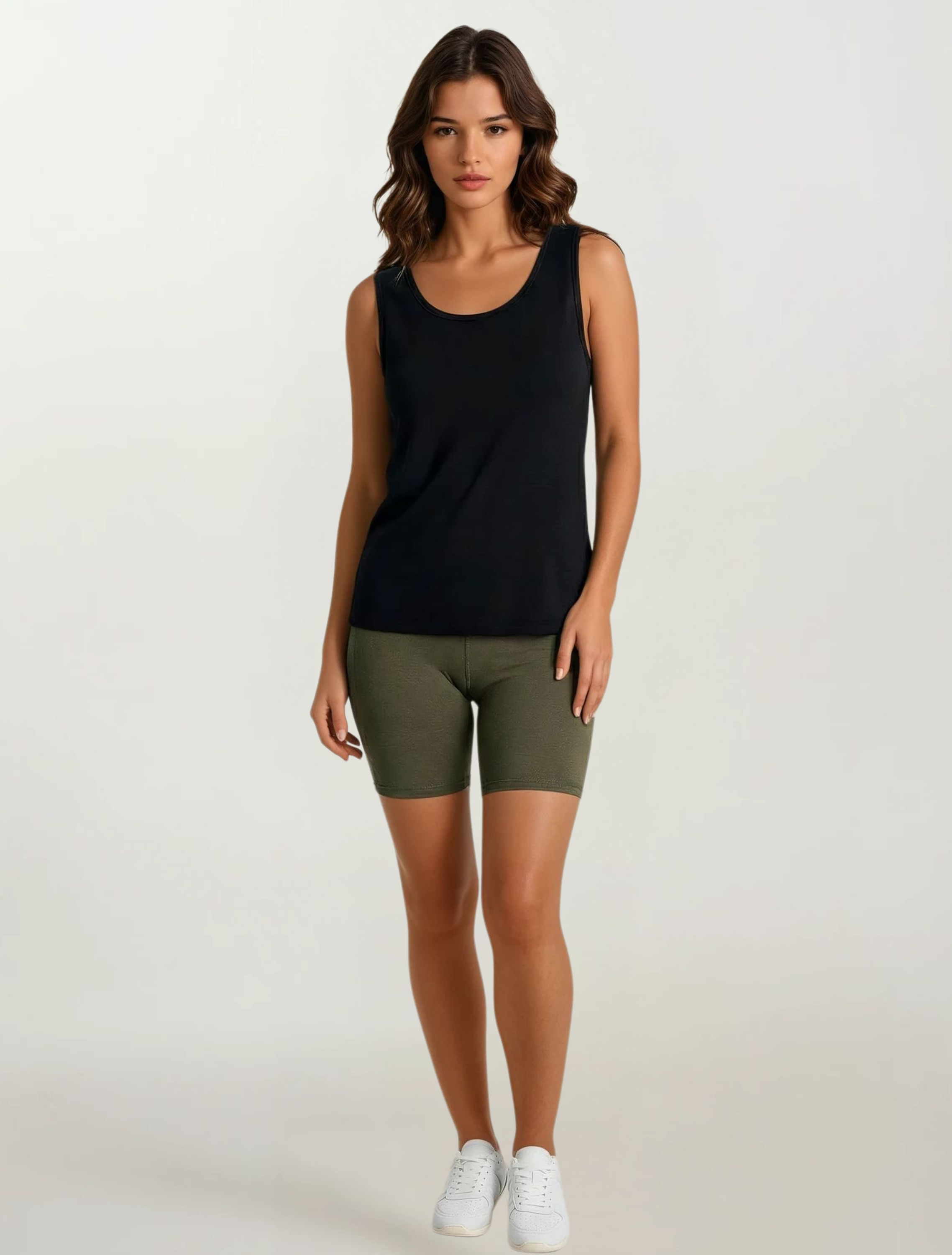 Woman wearing a black tank top and olive green shorts on a white background