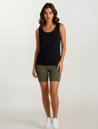 Woman wearing a black tank top and olive green shorts on a white background