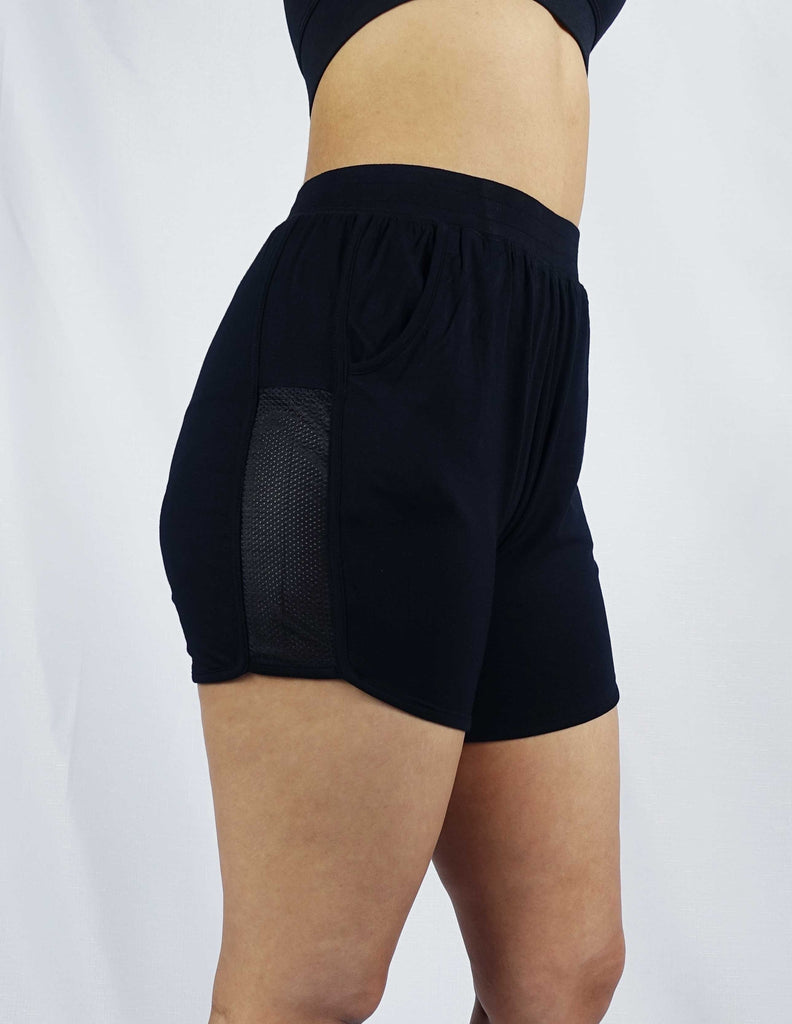Side view of black women's mid length shorts with mesh