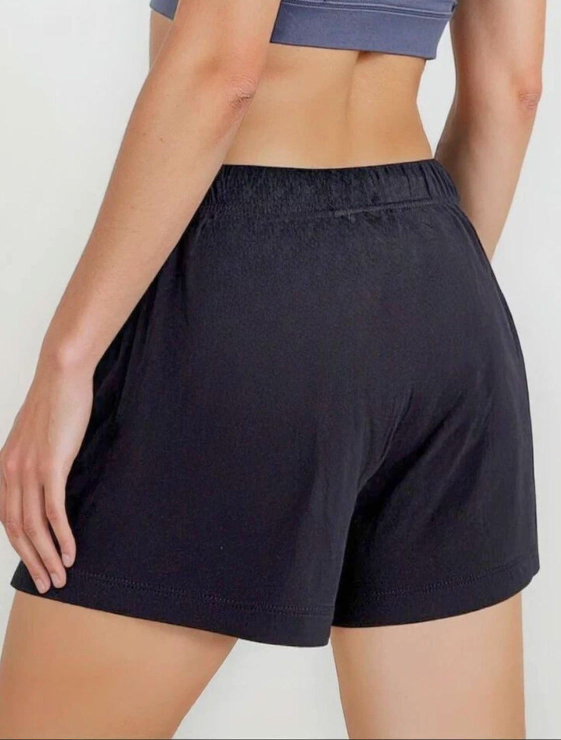 Person wearing a blue sports bra and black shorts on a white background