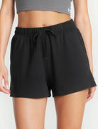 Girl wearing black shorts and a gray crop top on a white background