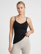Woman wearing a black tank top and gray leggings on a white background