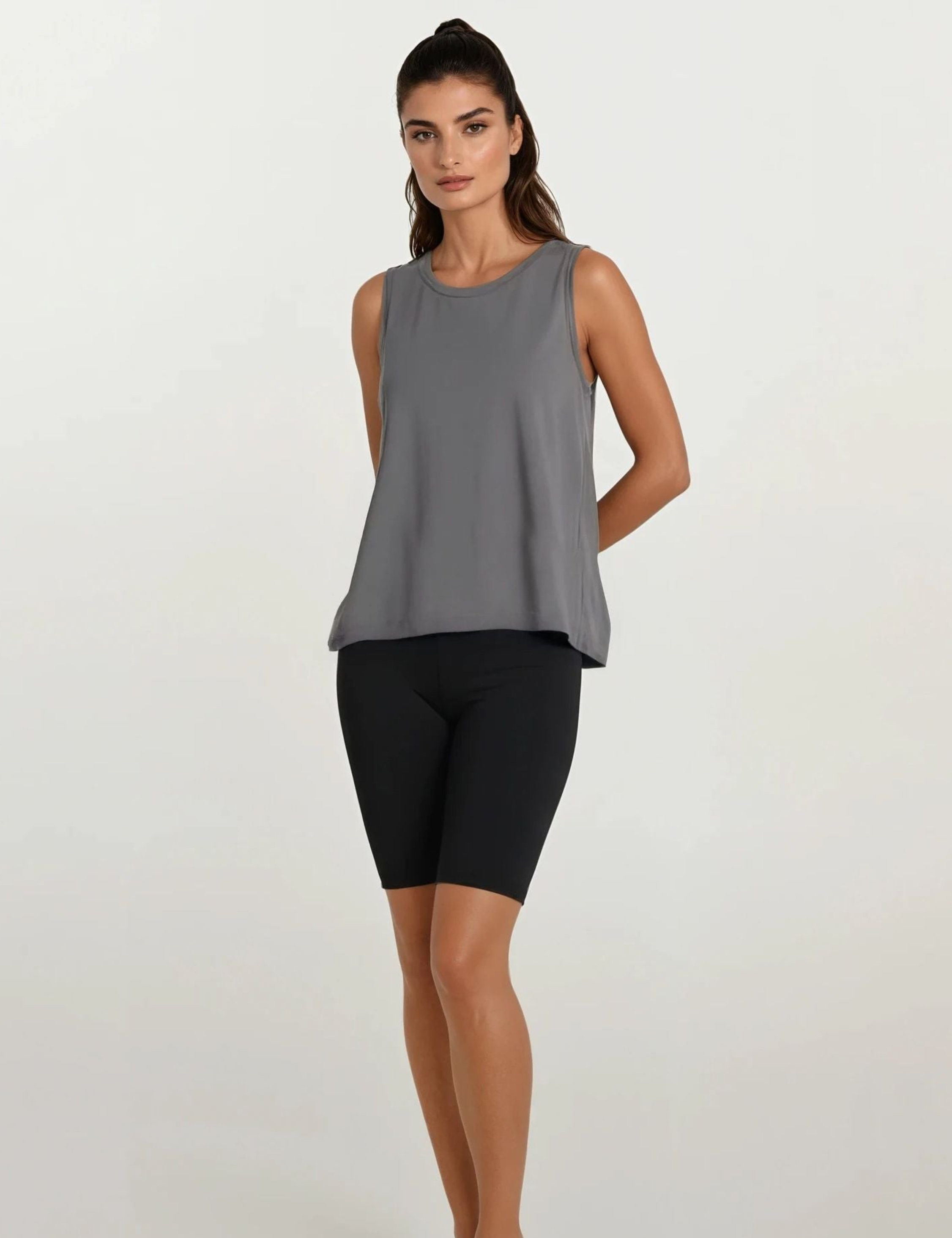 Woman wearing a gray sleeveless top and black shorts on a white background