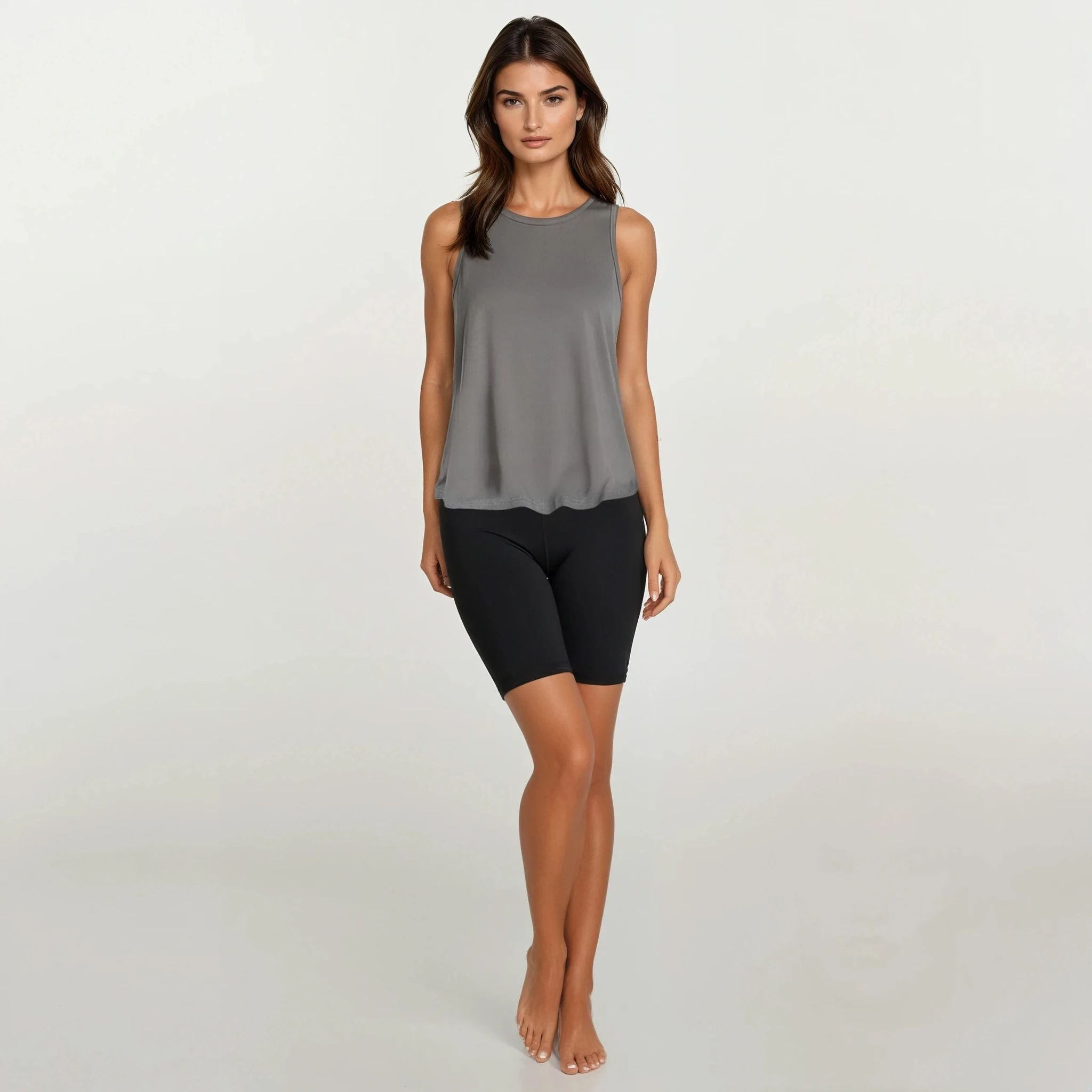Woman wearing a gray sleeveless top and black shorts on a white background