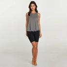 Woman wearing a gray sleeveless top and black shorts on a white background