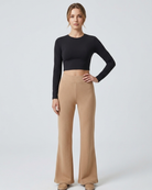Woman wearing a black long-sleeve top and beige wide-leg pants on a white background