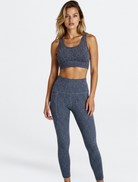 Woman wearing a blue patterned sports bra and leggings on a white background