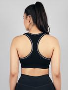Person wearing a black sports bra with tank top straps Womens Black ribbed-seamless-wirefree-sports bra-Bamboo super soft hypoallergenic breathable Tank Top on a gray background