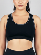 Black sports bra with silver trim Womens Black ribbed seamless-wirefree-bra-Bamboo super soft hypoallergenic breathable Tank orn by a person on a plain background