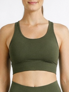 Woman wearing an olive green athletic outfit on a white background