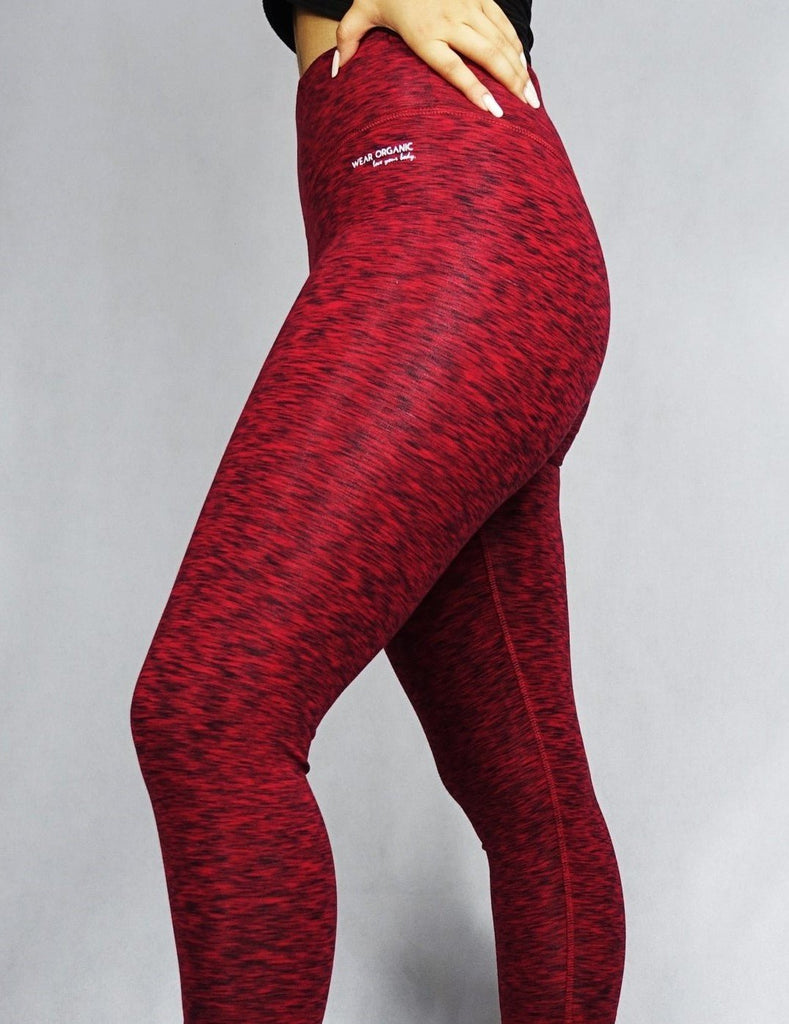 Side view of a model wearing red full length leggings, activewear